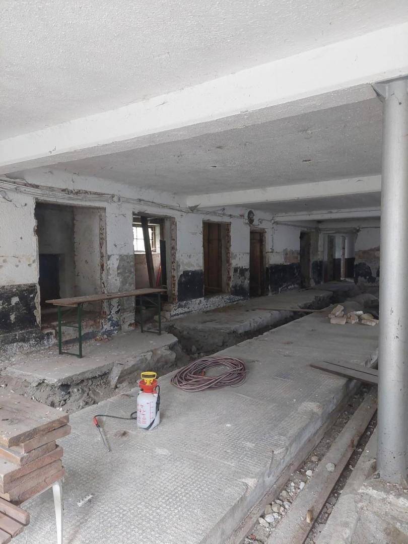 Großer Innenraum im Rohbauzustand mit Betonboden und freigelegten Wänden, bereit für die Renovierung.