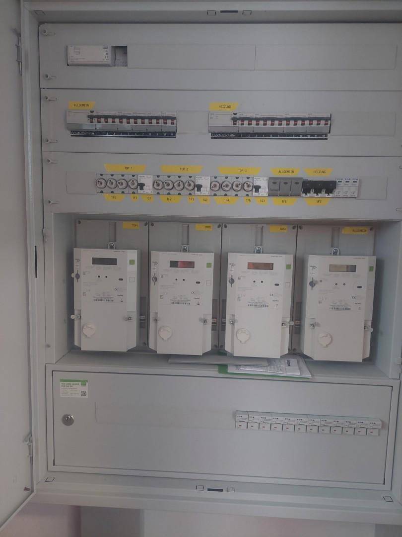 Elektrischer Verteilerkasten mit mehreren Stromzählern und Sicherungen.