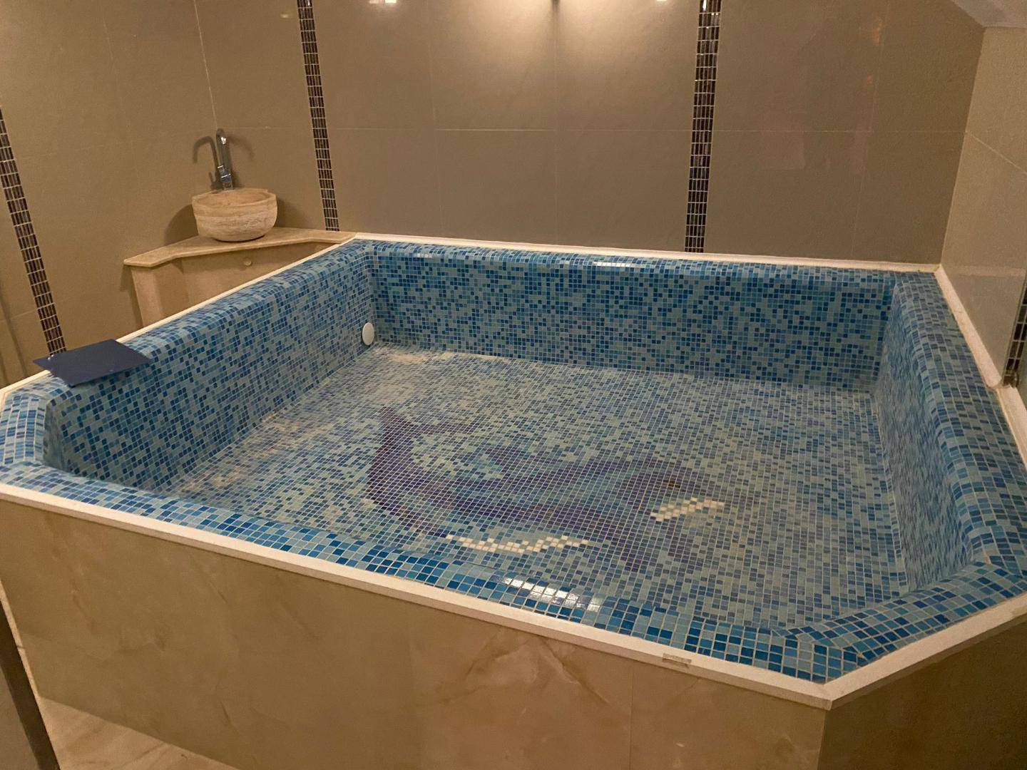 Großes, gefliestes Becken mit blauen Mosaikfliesen in einem modernen Wellnessbereich.
