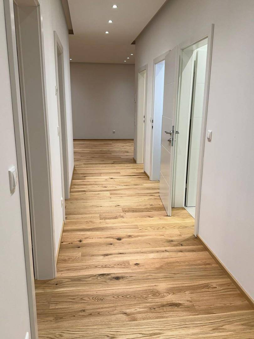Langer, heller Flur mit Holzboden und mehreren Türen, die zu verschiedenen Räumen führen.