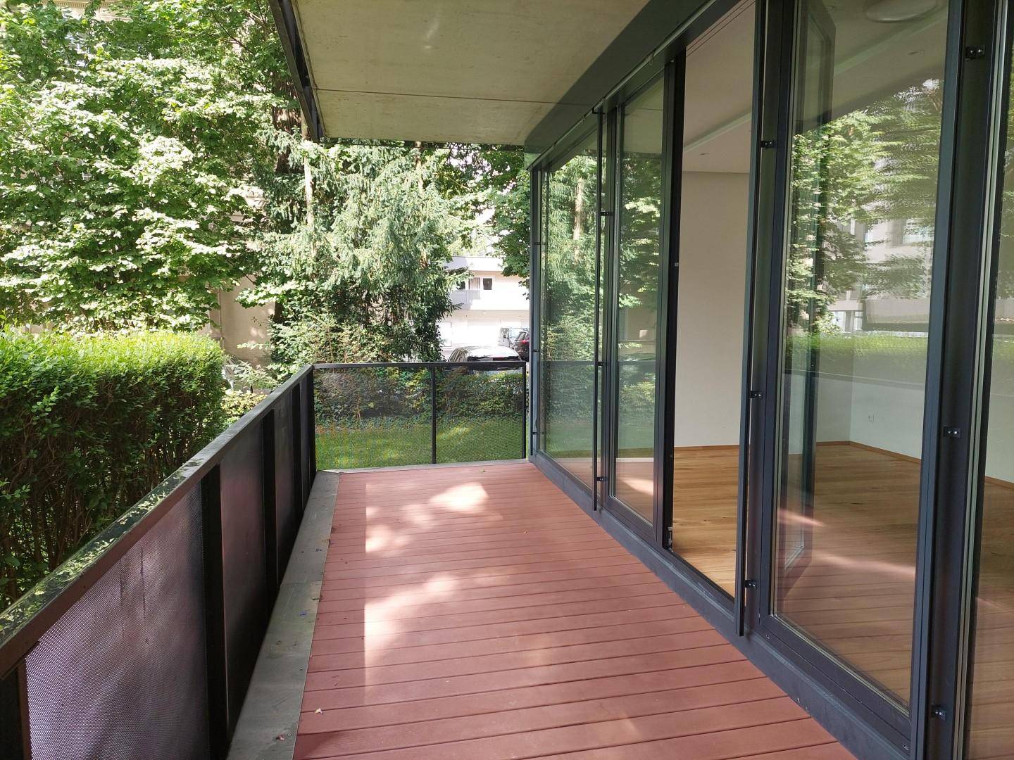 Geräumiger Balkon mit Holzboden und Blick ins Grüne, ideal für entspannte Stunden im Freien.