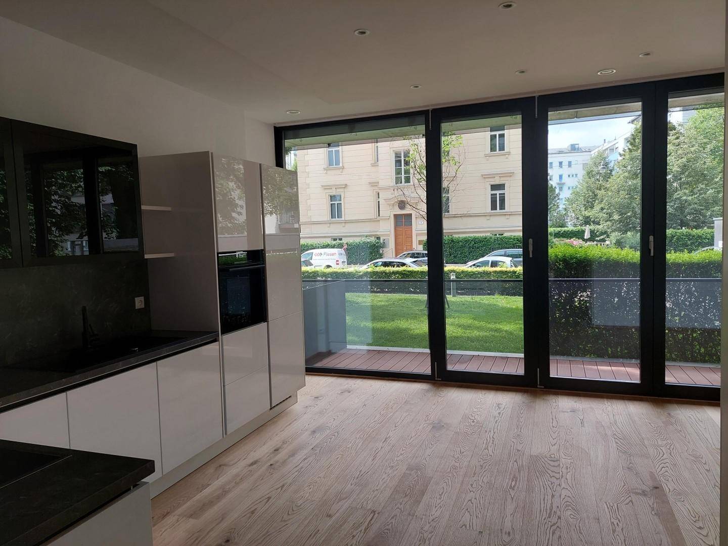 Offene Küche mit modernen Geräten und großzügigem Blick ins Grüne durch bodentiefe Fenster.