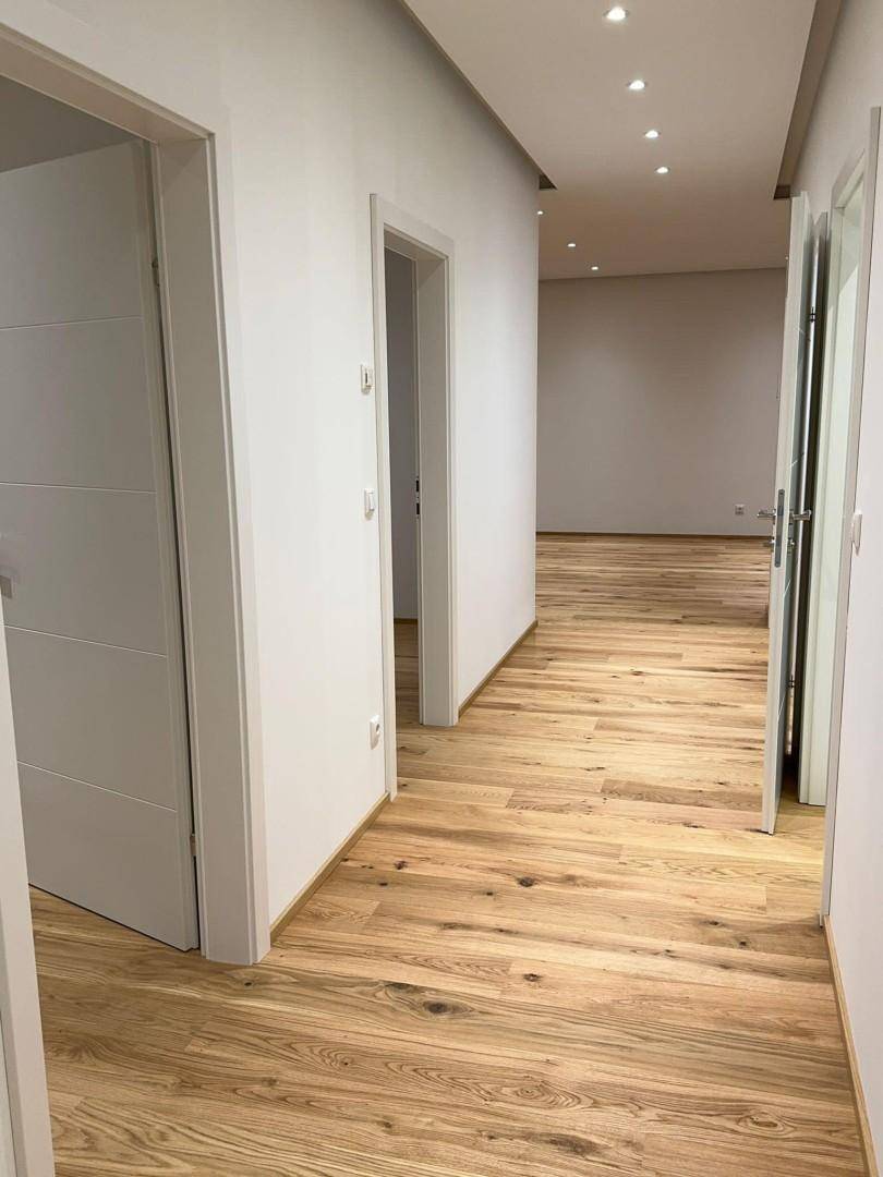 Heller Flur mit Holzfußboden und modernen weißen Türen, der zu weiteren Räumen führt.