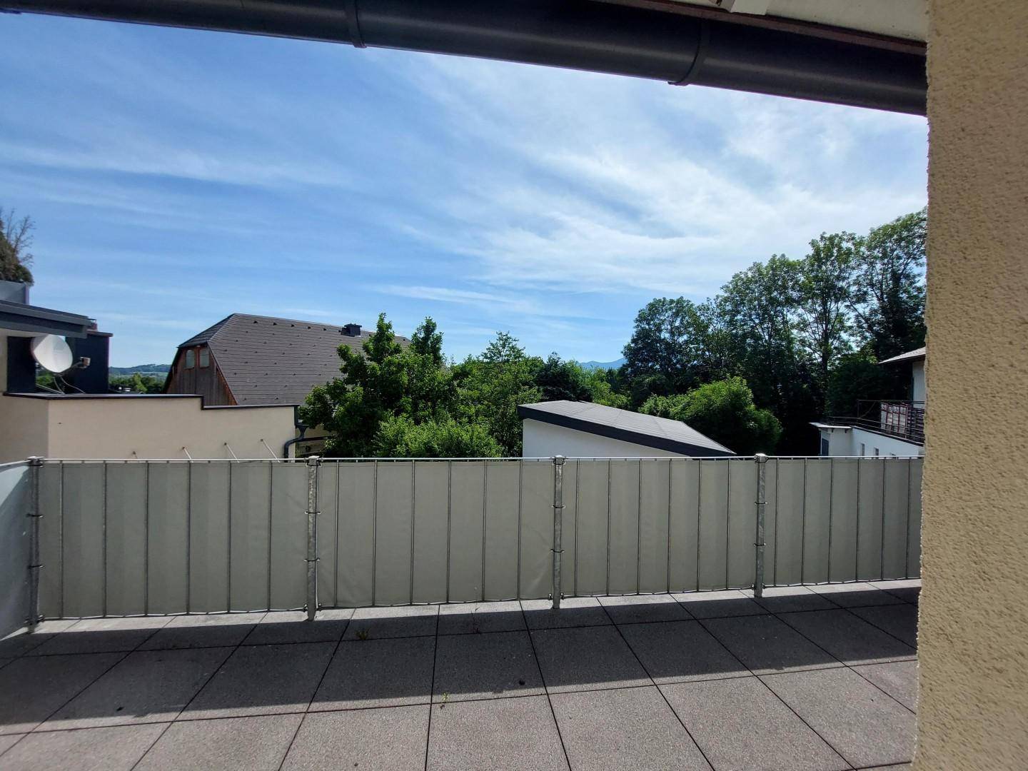 Große Terrasse mit Fliesenboden und weitem Blick auf die grüne Umgebung und Berge.