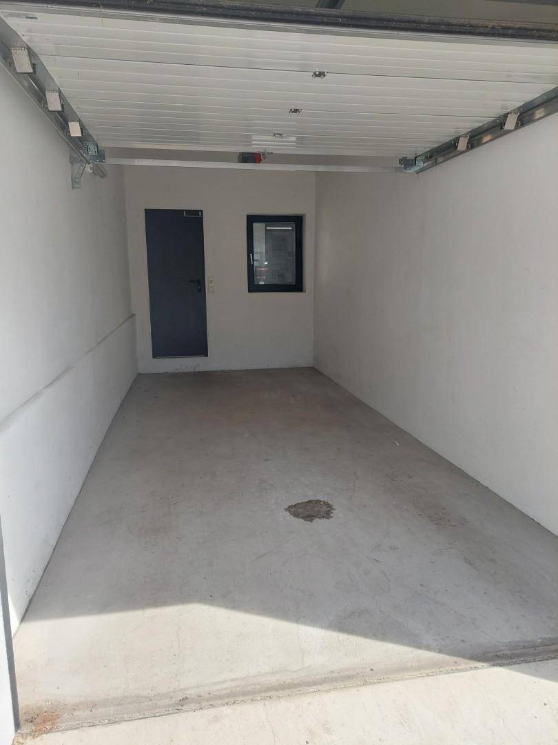 Geräumige Garage mit Betonboden, weiß gestrichenen Wänden und einem kleinen Fenster.