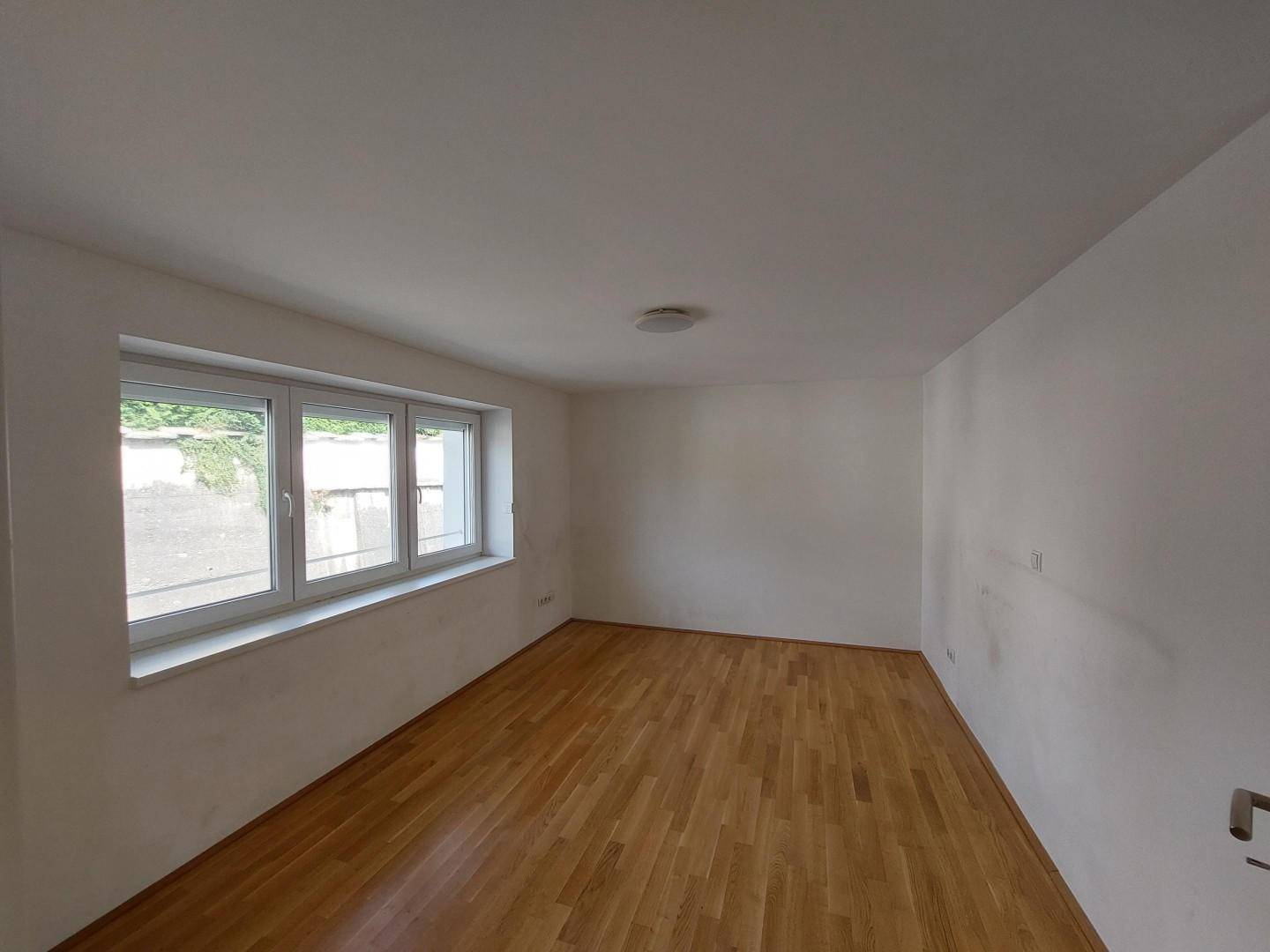 Helles Schlafzimmer mit drei Fenstern und schönem Parkettboden.