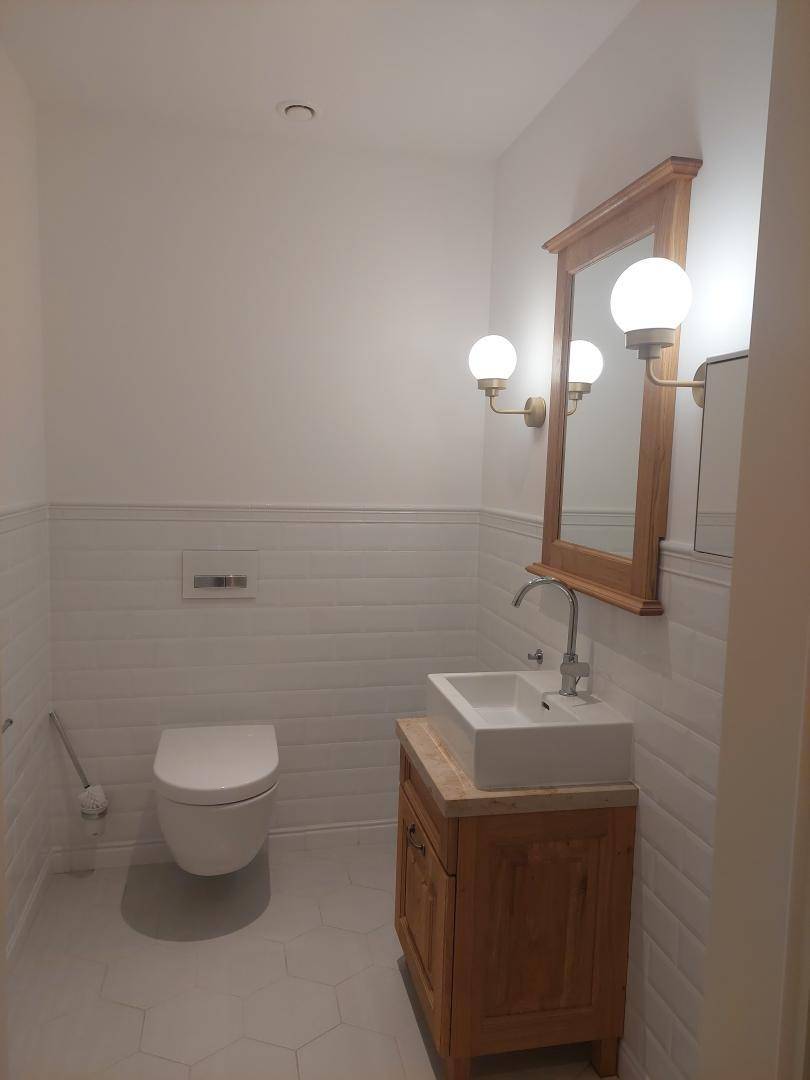 Gäste-WC mit modernem Waschtisch, Spiegel und Wand-WC.