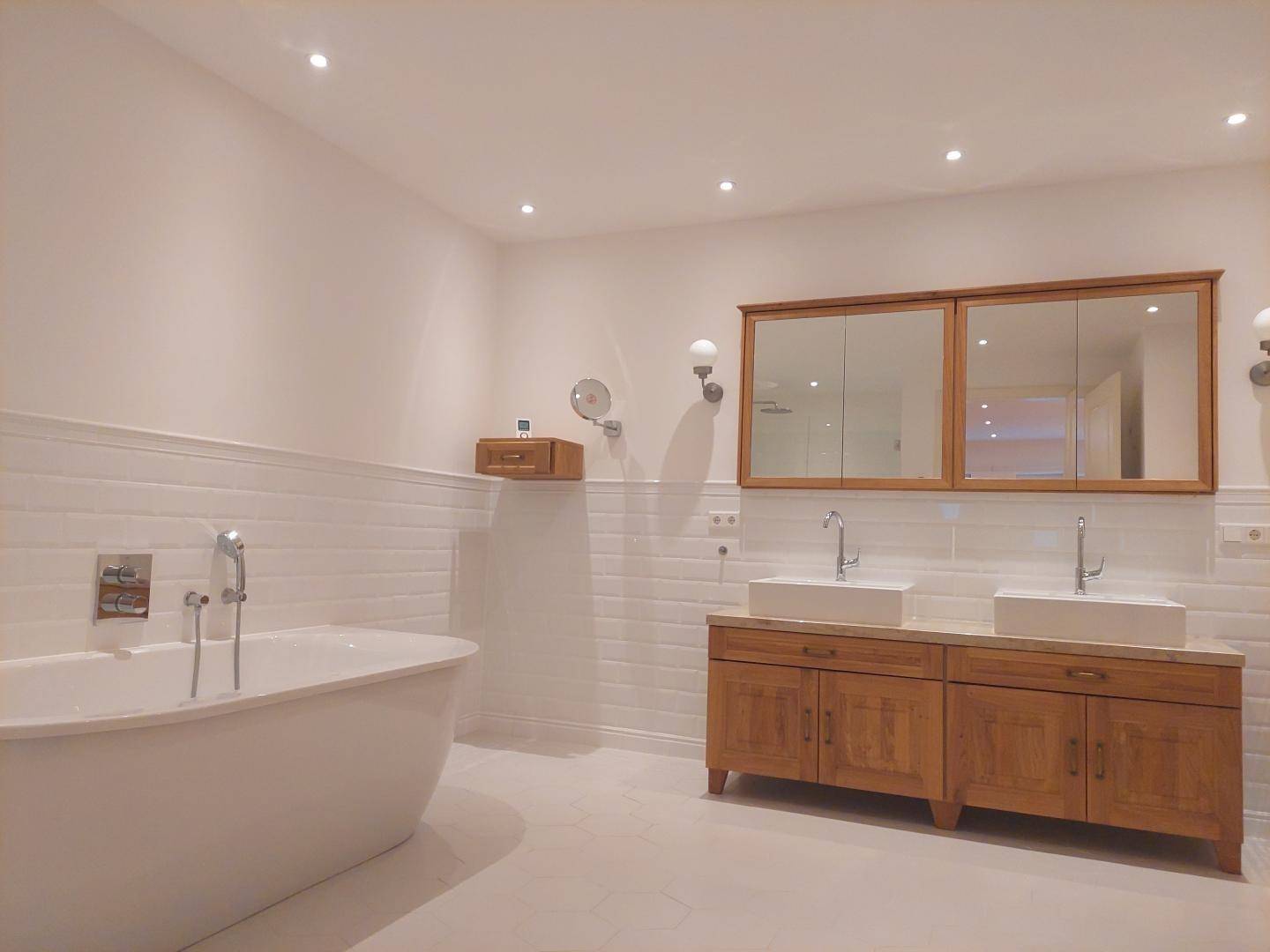 Elegantes Badezimmer mit freistehender Badewanne, Doppelwaschbecken und Holzschränken.