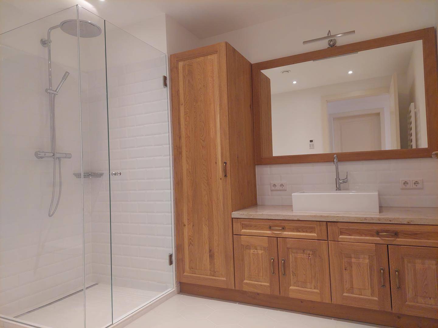 Modernes Badezimmer mit begehbarer Dusche, Holzwaschtisch und großem Spiegel.