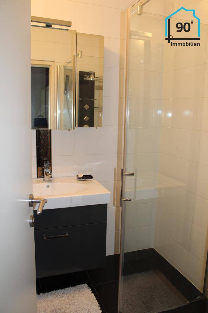 Modernes Badezimmer mit Duschkabine, Waschtisch und Spiegelschrank.