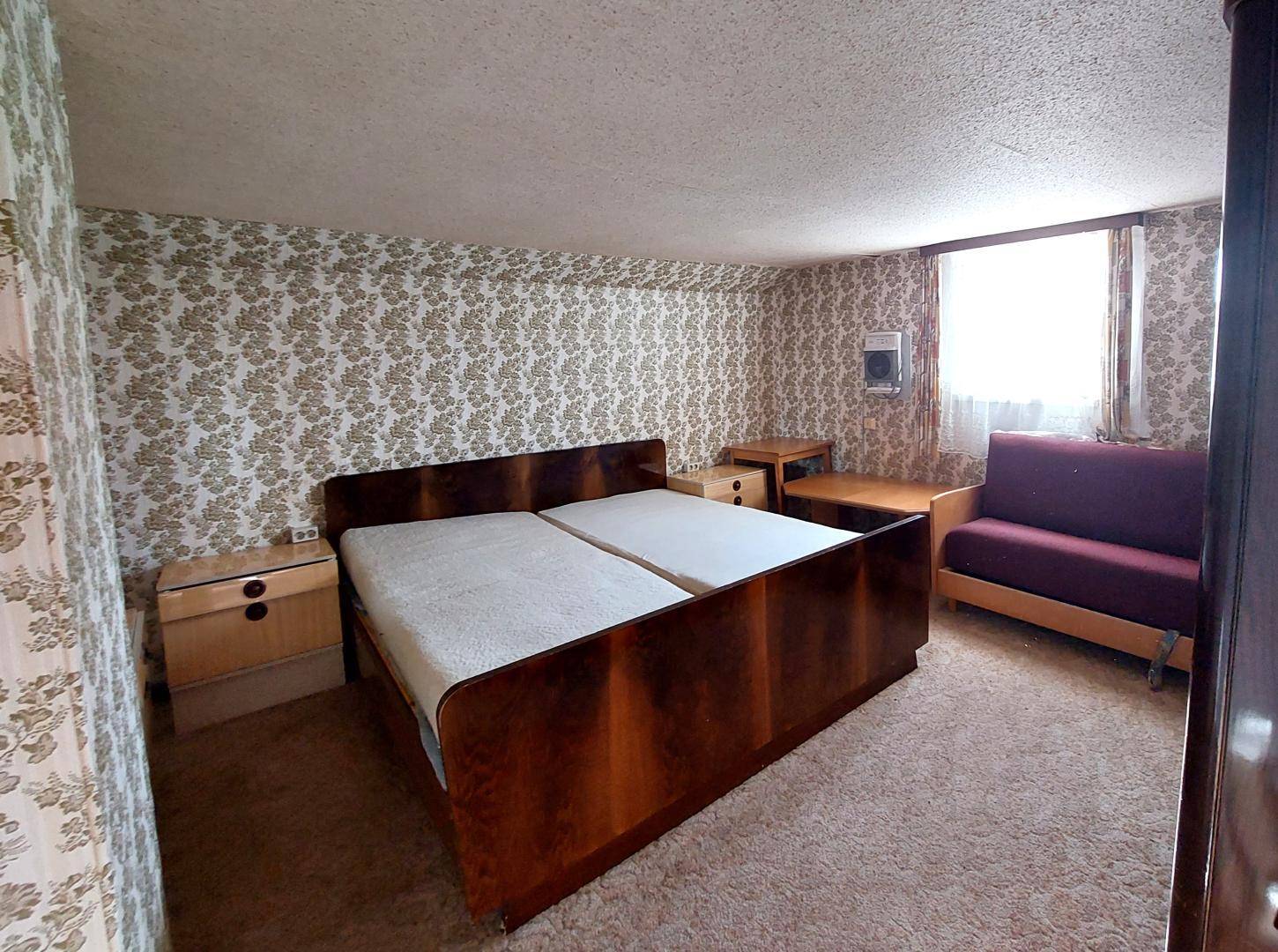Schlafzimmer mit Doppelbett, floraler Tapete und Teppichboden in traditionellem Stil.