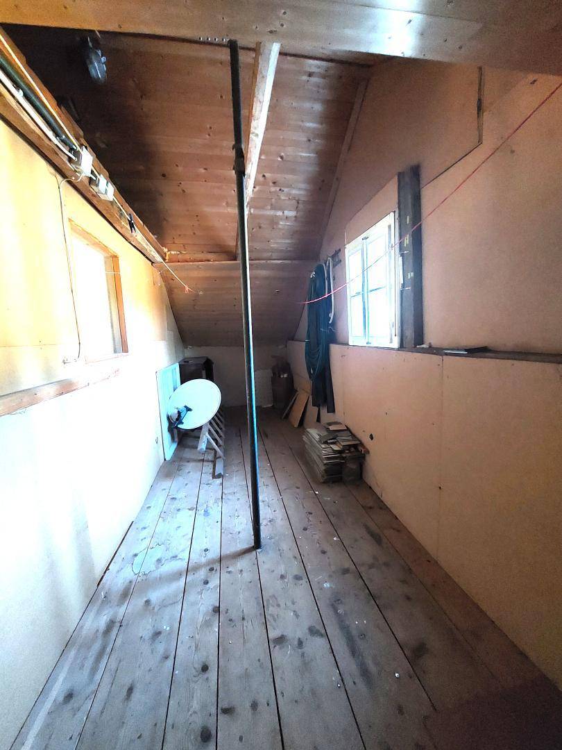 Dachboden mit Holzboden, schrägen Wänden und sichtbaren Balken, als Lagerraum nutzbar.