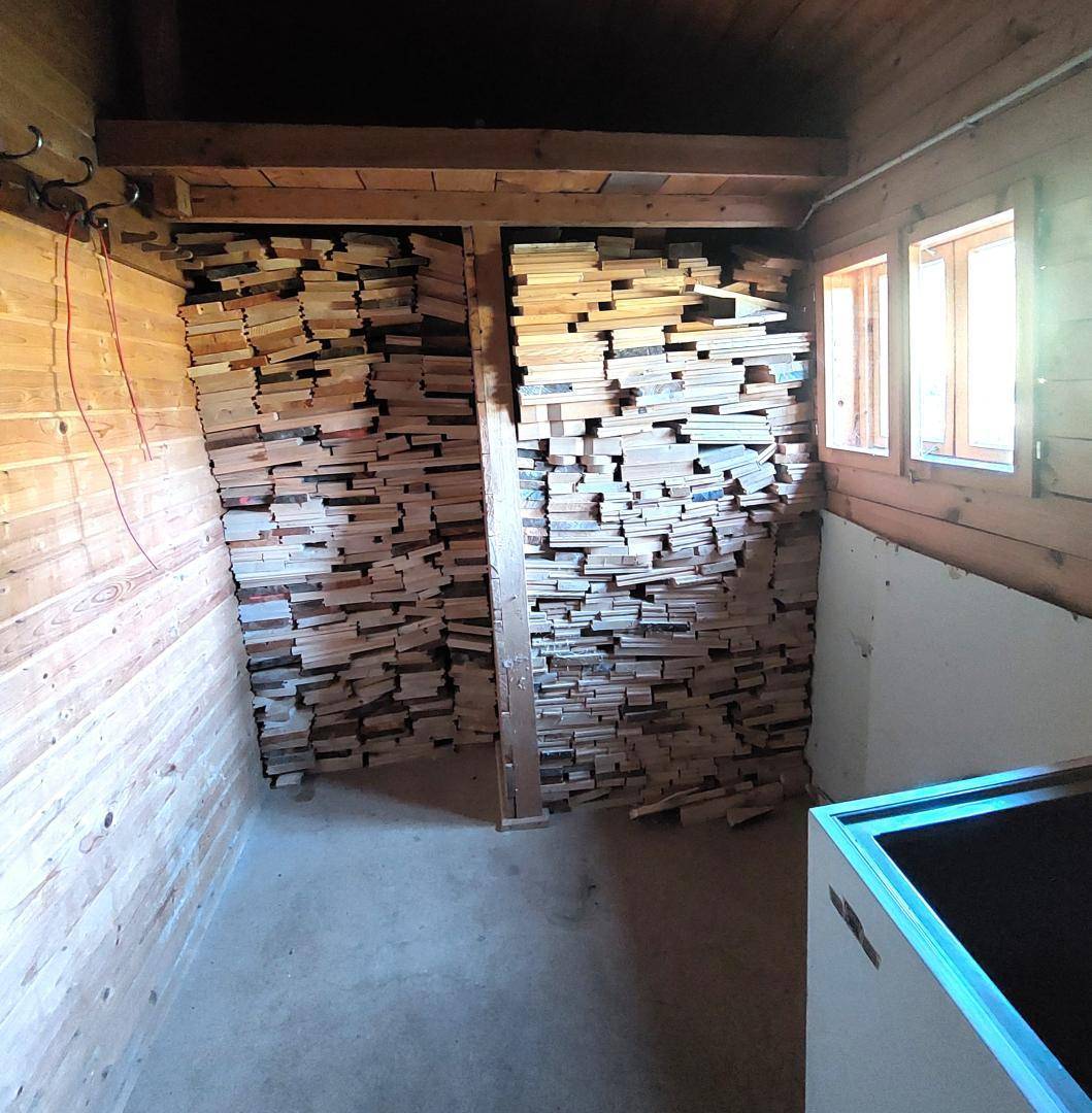 Lagerraum mit gestapeltem Holz und Holzverkleidung, ideal für Brennholz.