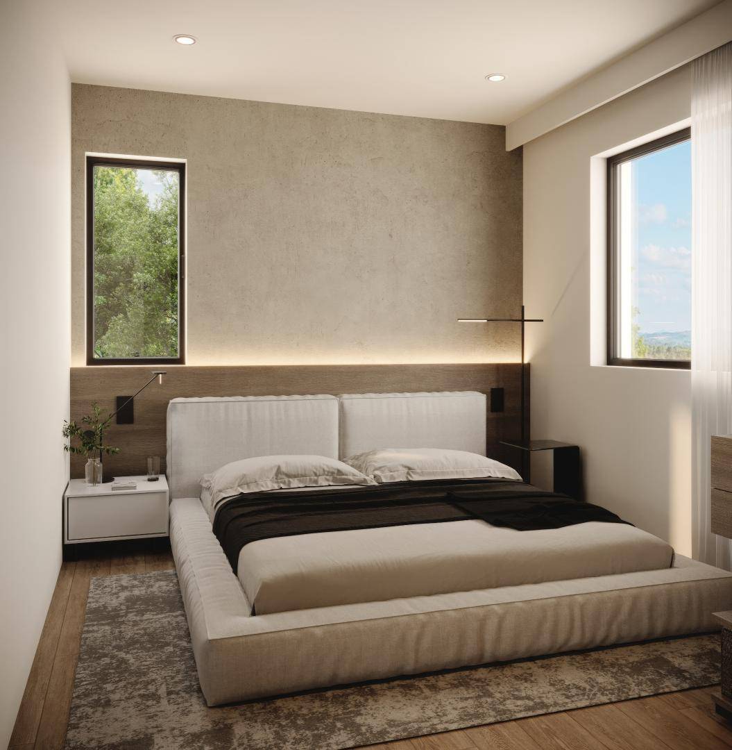 Helles Schlafzimmer mit großem Bett, zwei Fenstern und moderner, minimalistischer Einrichtung.