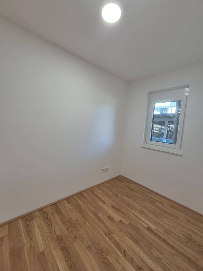 Kleines, helles Zimmer mit Parkettboden und Fenster, ideal als Kinder- oder Arbeitszimmer.