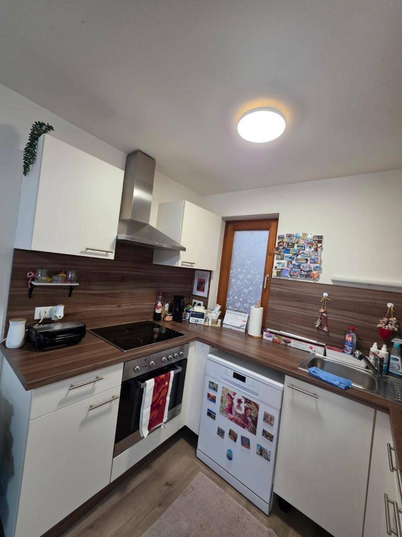 Moderne Küche mit Kochfeld, Dunstabzugshaube und Spülbereich, ideal für den täglichen Gebrauch.