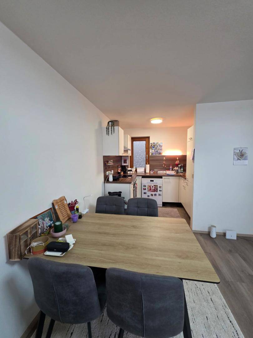Heller Essbereich mit Holztisch und Blick in die angrenzende, funktionale Küche.
