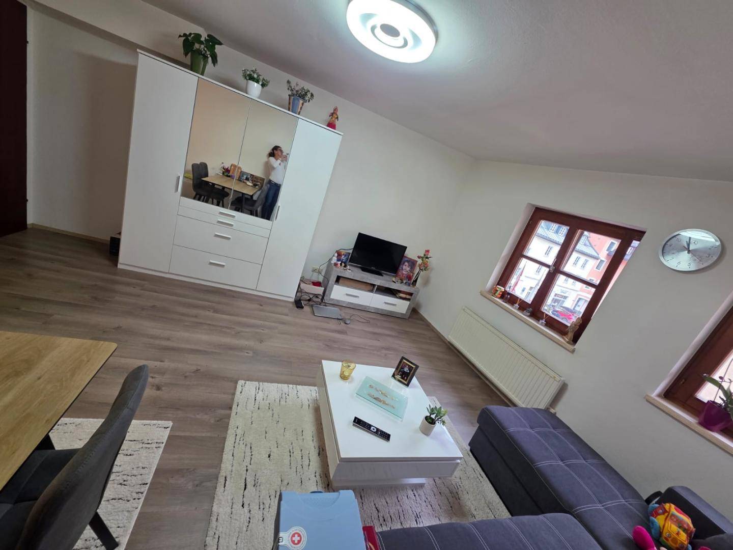 Gemütlicher Wohnbereich mit Sofa, Couchtisch und einem großen Schrank mit Spiegelfront.