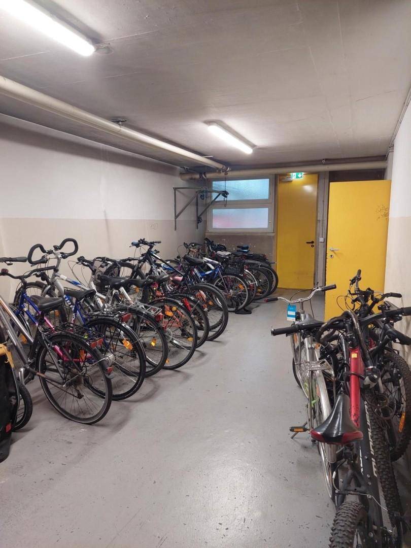Fahrradraum im Untergeschoss mit zahlreichen Fahrrädern und einem Fenster.