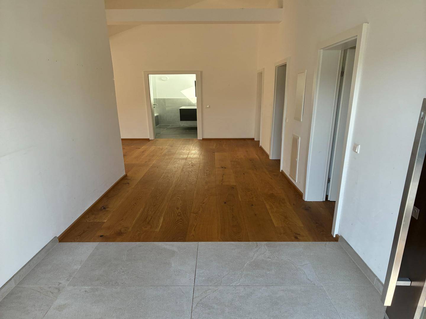 Heller Flur mit Holzboden und Zugang zu verschiedenen Räumen, inklusive einem Badezimmer.
