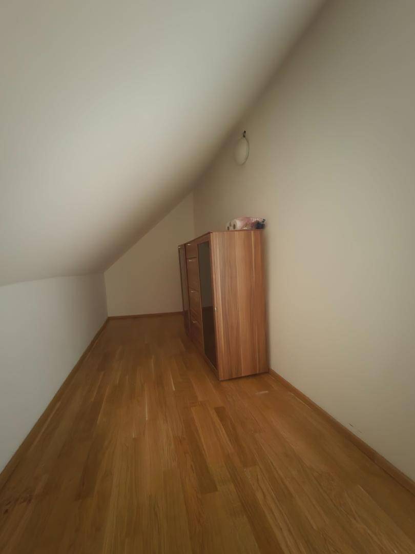 Kleiner Raum unter der Dachschräge mit Parkettboden und einem Schrank.