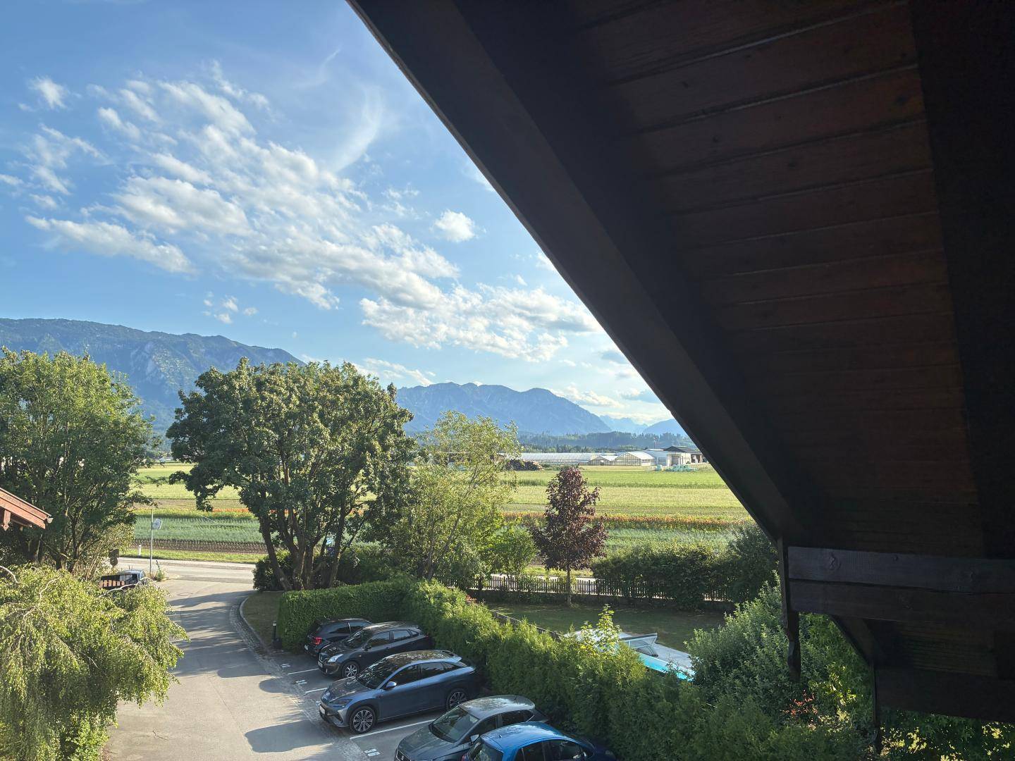 Panoramablick vom Balkon auf die Parkplätze, grüne Landschaft und die majestätischen Berge.