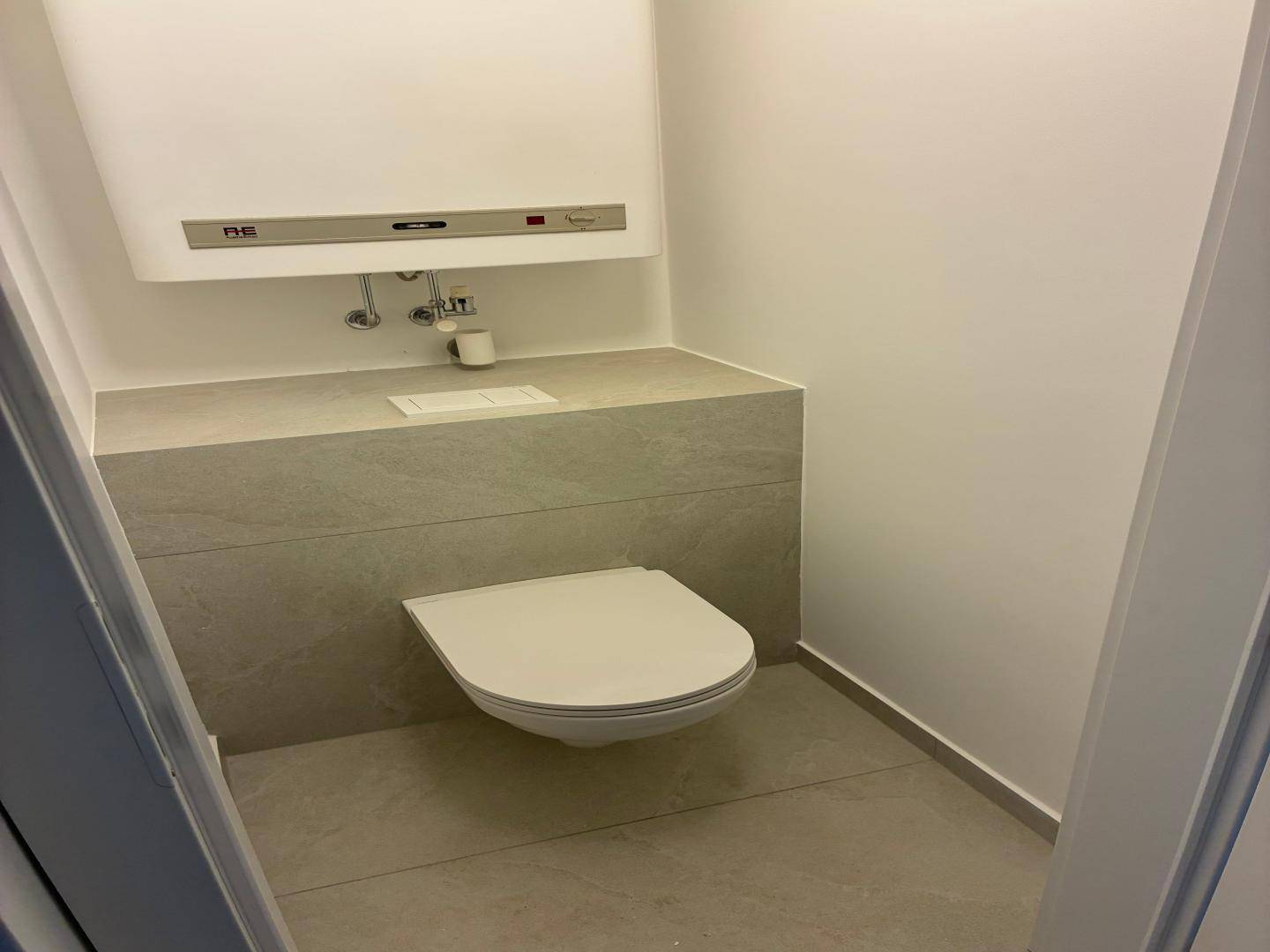Kleines Gäste-WC mit wandhängender Toilette und modernen grauen Fliesen.