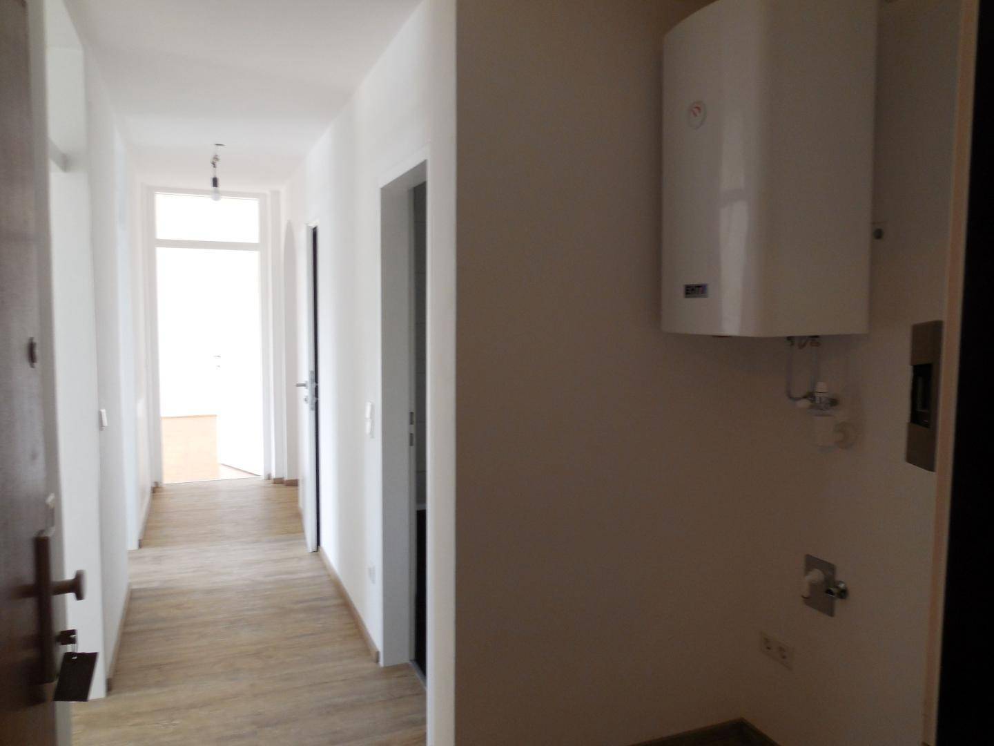 Heller Flur mit Laminatboden und weiß gestrichenen Wänden, führt zu weiteren Räumen der Wohnung.