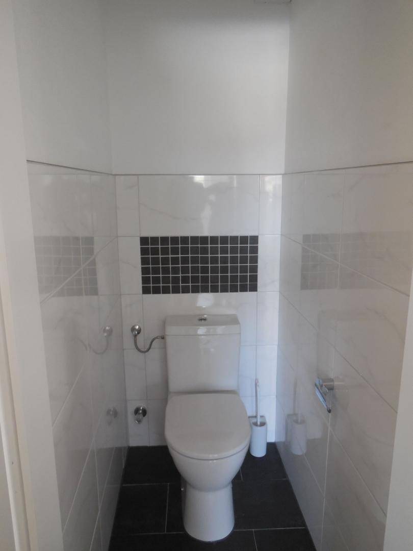 Separates WC mit Toilette und einer Kombination aus weißen und schwarzen Fliesen an den Wänden.
