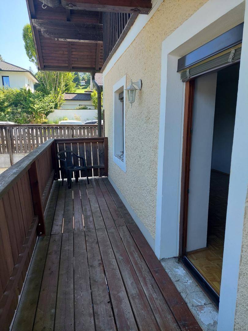 Holzbalkon mit Sitzgelegenheiten und Blick ins Grüne, ideal zum Entspannen im Freien.