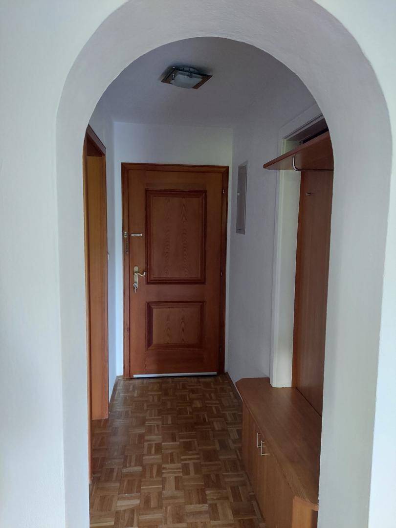 Eingangsbereich mit Holztür, Parkettboden und praktischer Garderobe.
