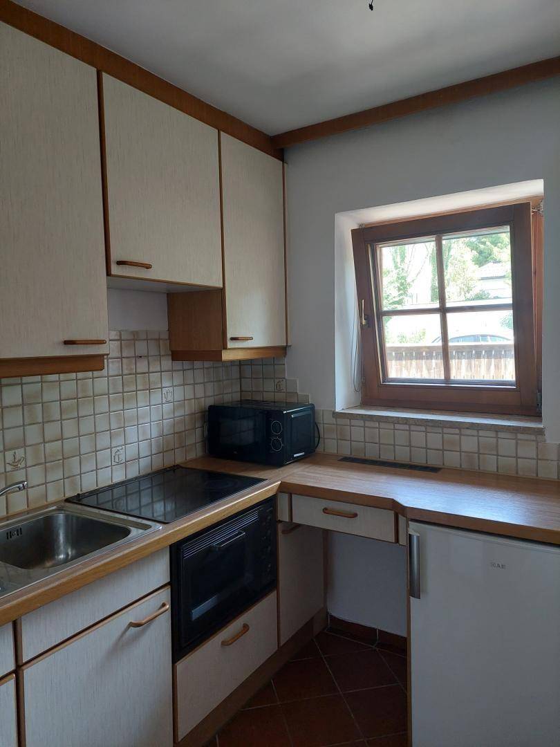 Funktionale Küche mit hellen Holzschränken, Fliesenrückwand und Fenster.