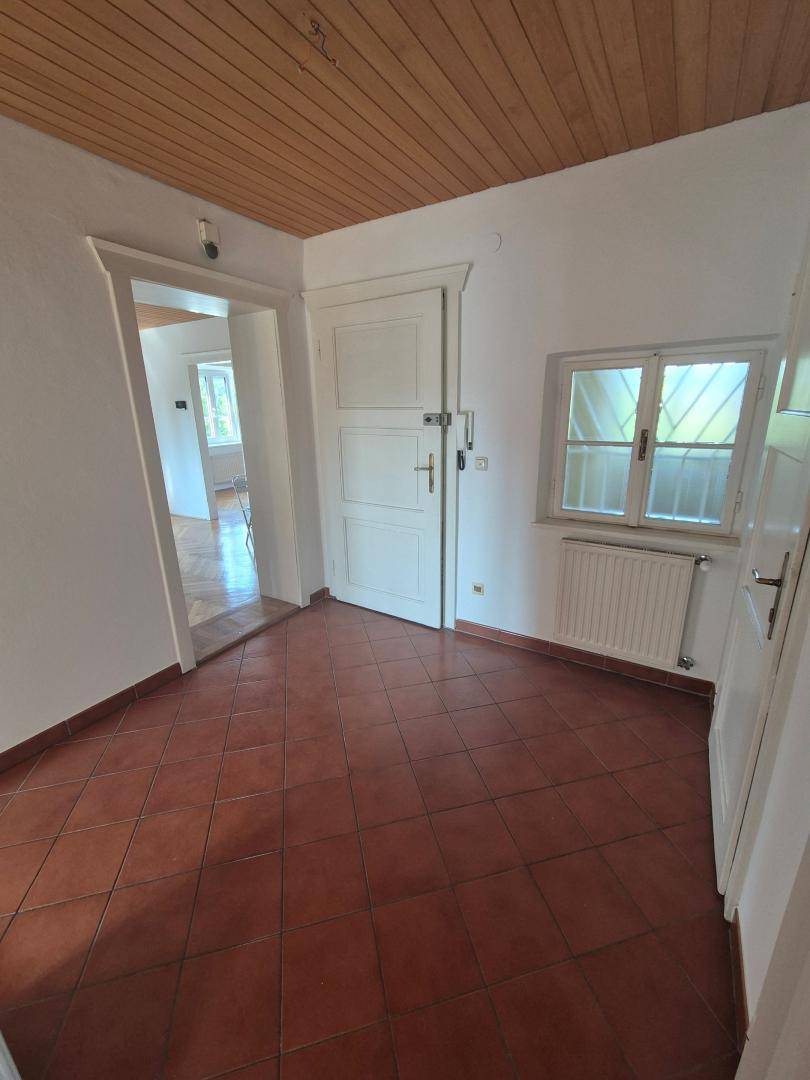 Eingangsbereich mit Terrakottafliesen, Holzdecke und Zugang zu weiteren Räumen.
