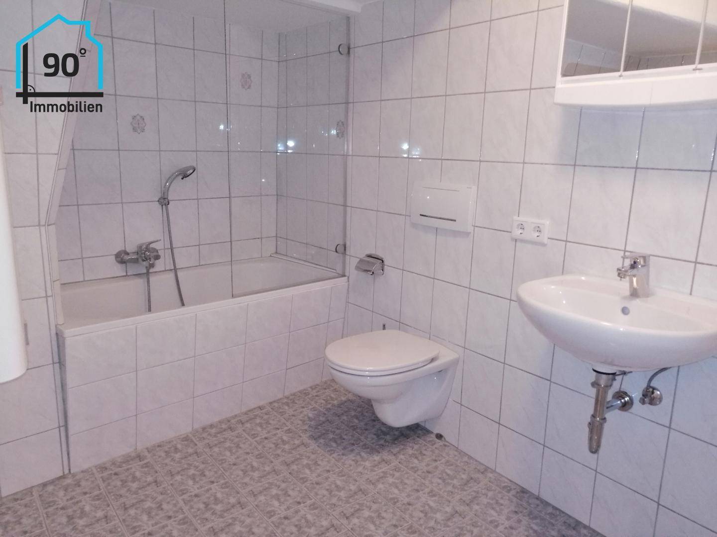 Gefliestes Badezimmer mit Badewanne, WC und Waschbecken, in hellem und sauberem Zustand, gut gepflegt.