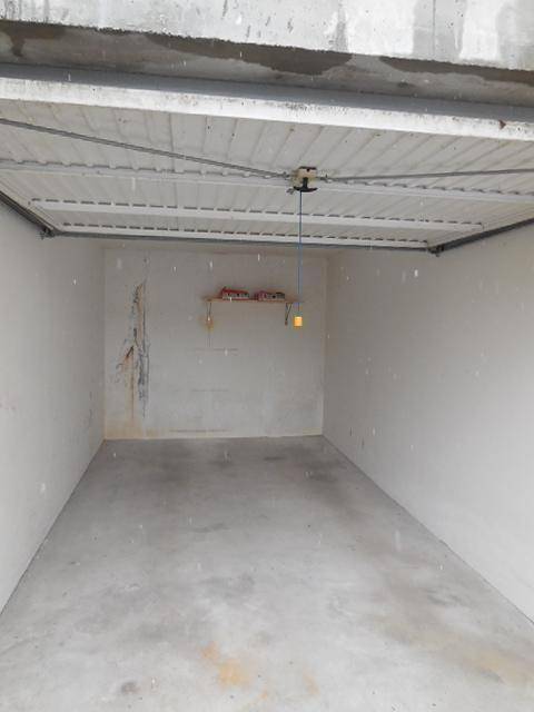 Leere Garage mit Betonboden und unverputzten Wänden, bereit zur Nutzung.