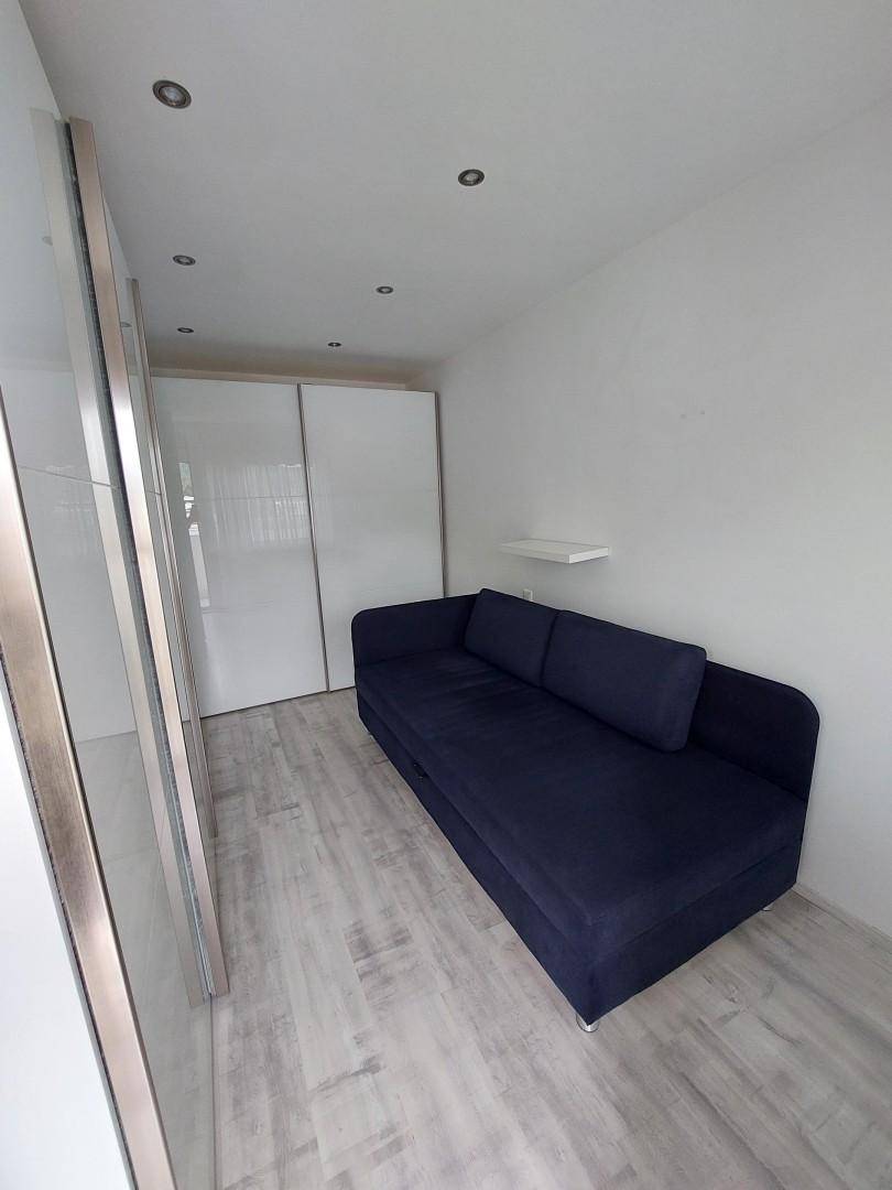 Kleines Schlafzimmer mit Schlafsofa und weißem Schiebetürenschrank, hell und funktional.