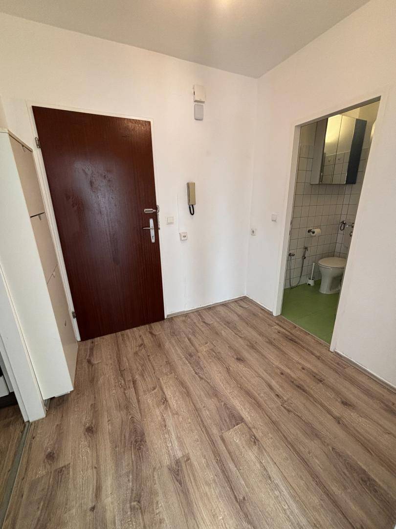 Flur mit Laminatboden und Zugang zu einem Badezimmer oder Gäste-WC.