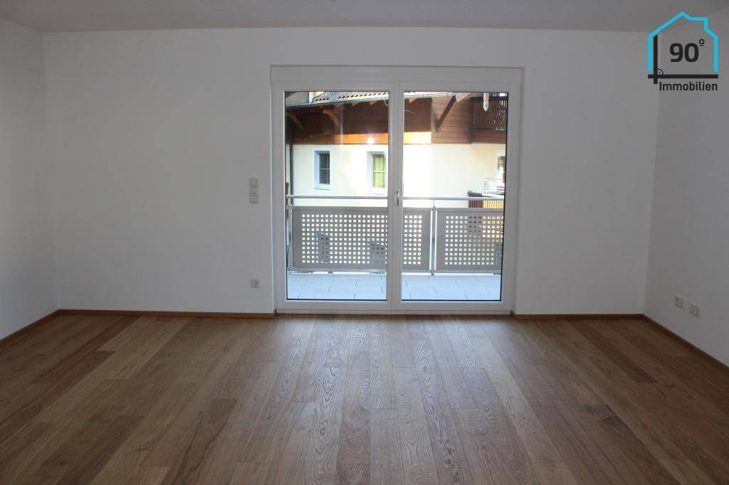 Heller Raum mit Holzboden und großem Balkonzugang.