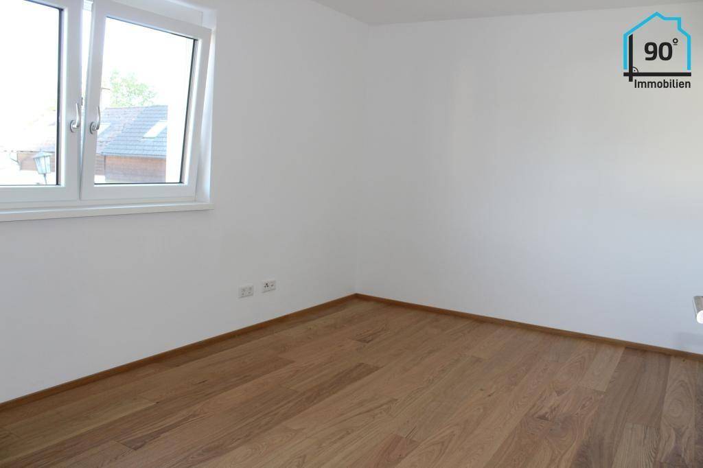 Leeres Zimmer mit Parkettboden und weiß gestrichenen Wänden.