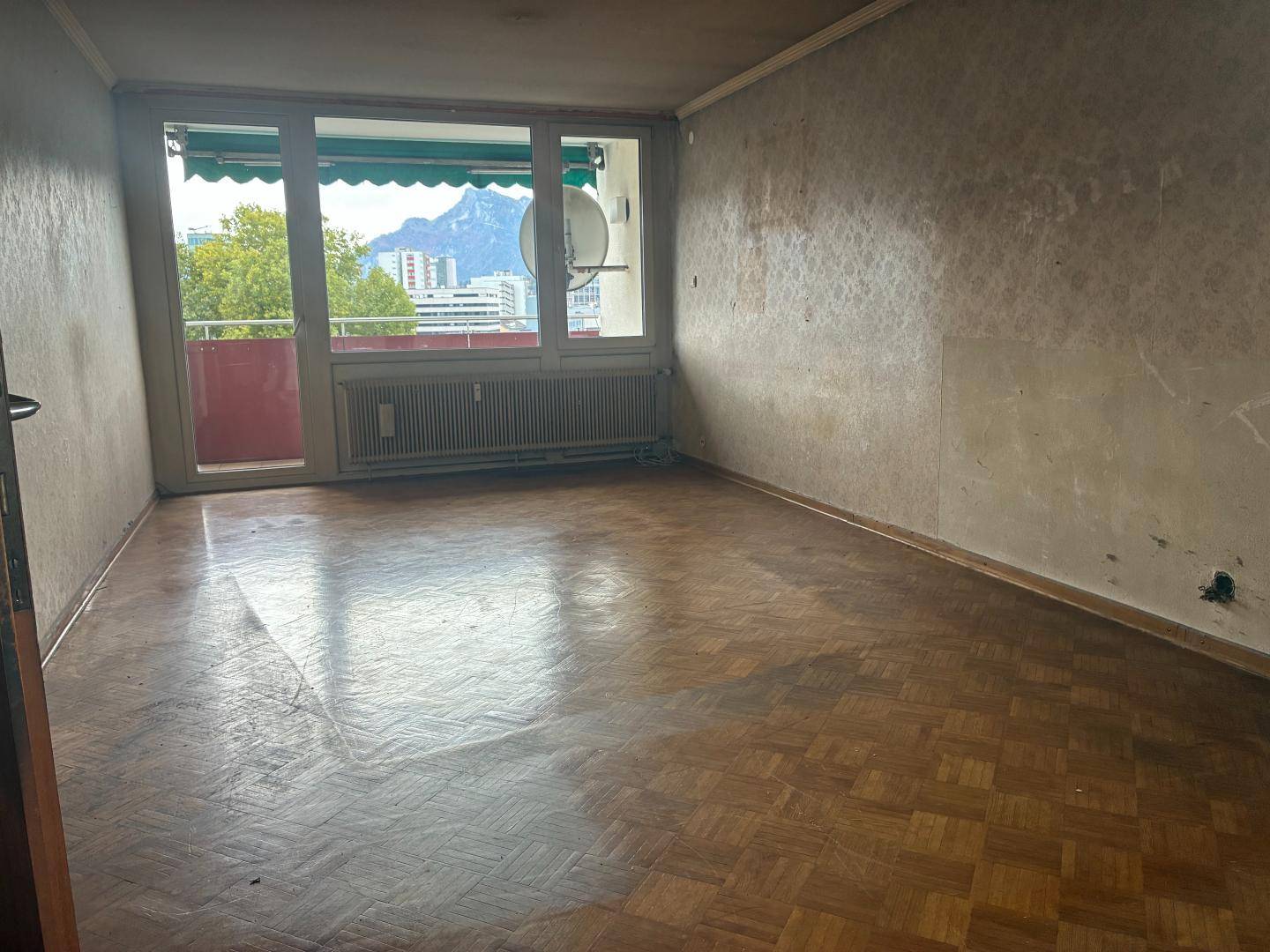 Geräumiges Zimmer mit Parkettboden und Zugang zum Balkon, bereit für eine Modernisierung.