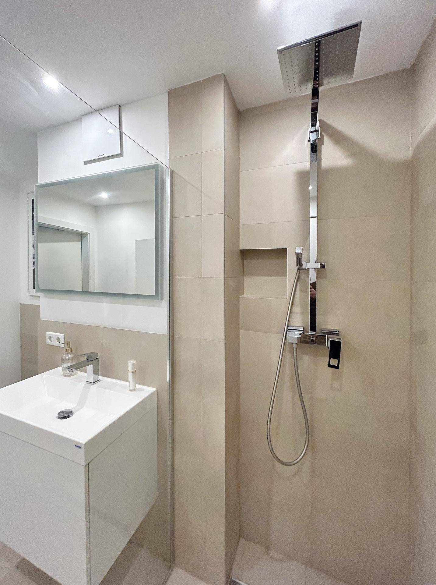 Modernes Badezimmer mit begehbarer Dusche, Einzelwaschbecken und Spiegelschrank.
