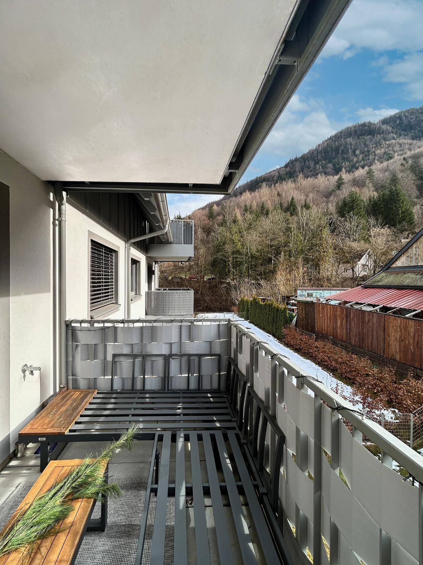 Balkon mit Bergblick und einfacher Sitzgelegenheit, umgeben von Natur.