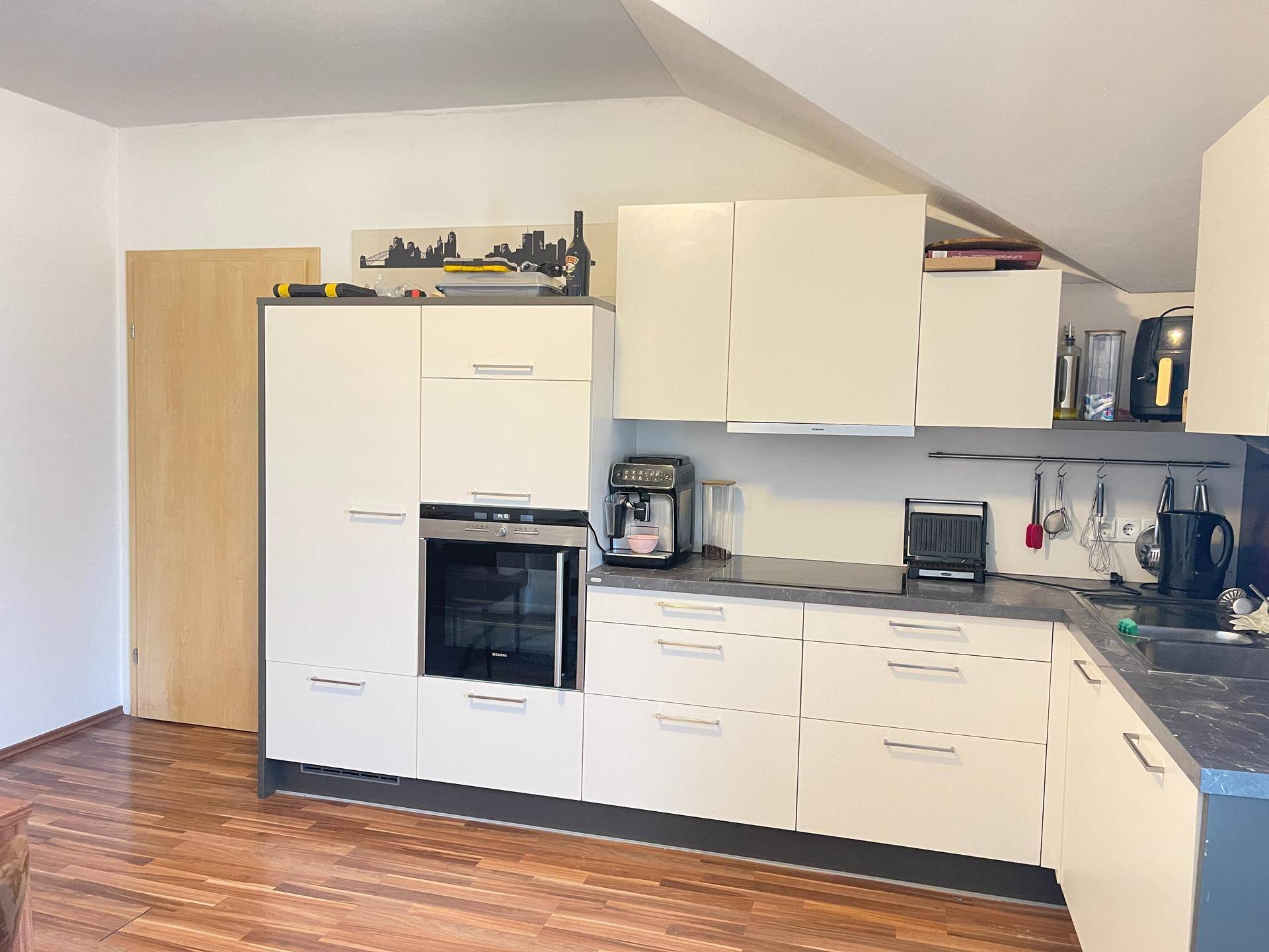 Moderne Einbauküche in Weiß mit integriertem Backofen und viel Stauraum.