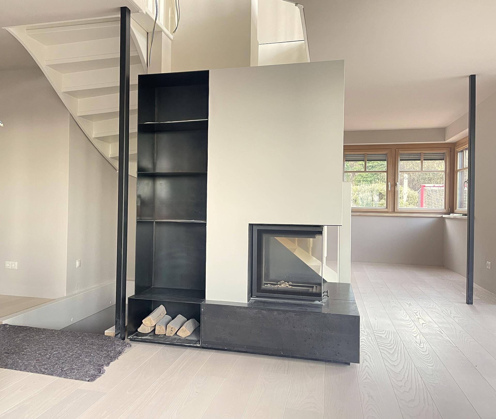 Moderner Wohnbereich mit integriertem Kamin, Holzablage und Treppenaufgang, stilvoll gestaltet.