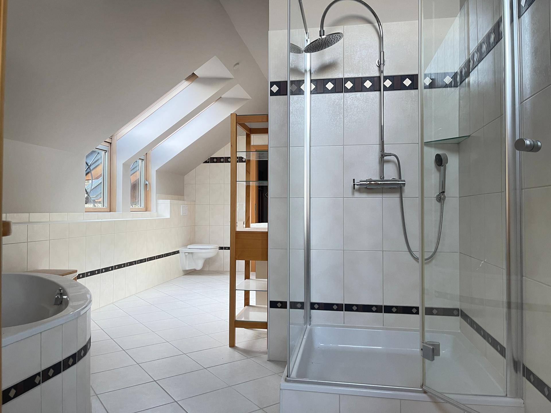 Helles Badezimmer mit Duschkabine, Eckbadewanne und Dachschräge, in gutem Zustand.