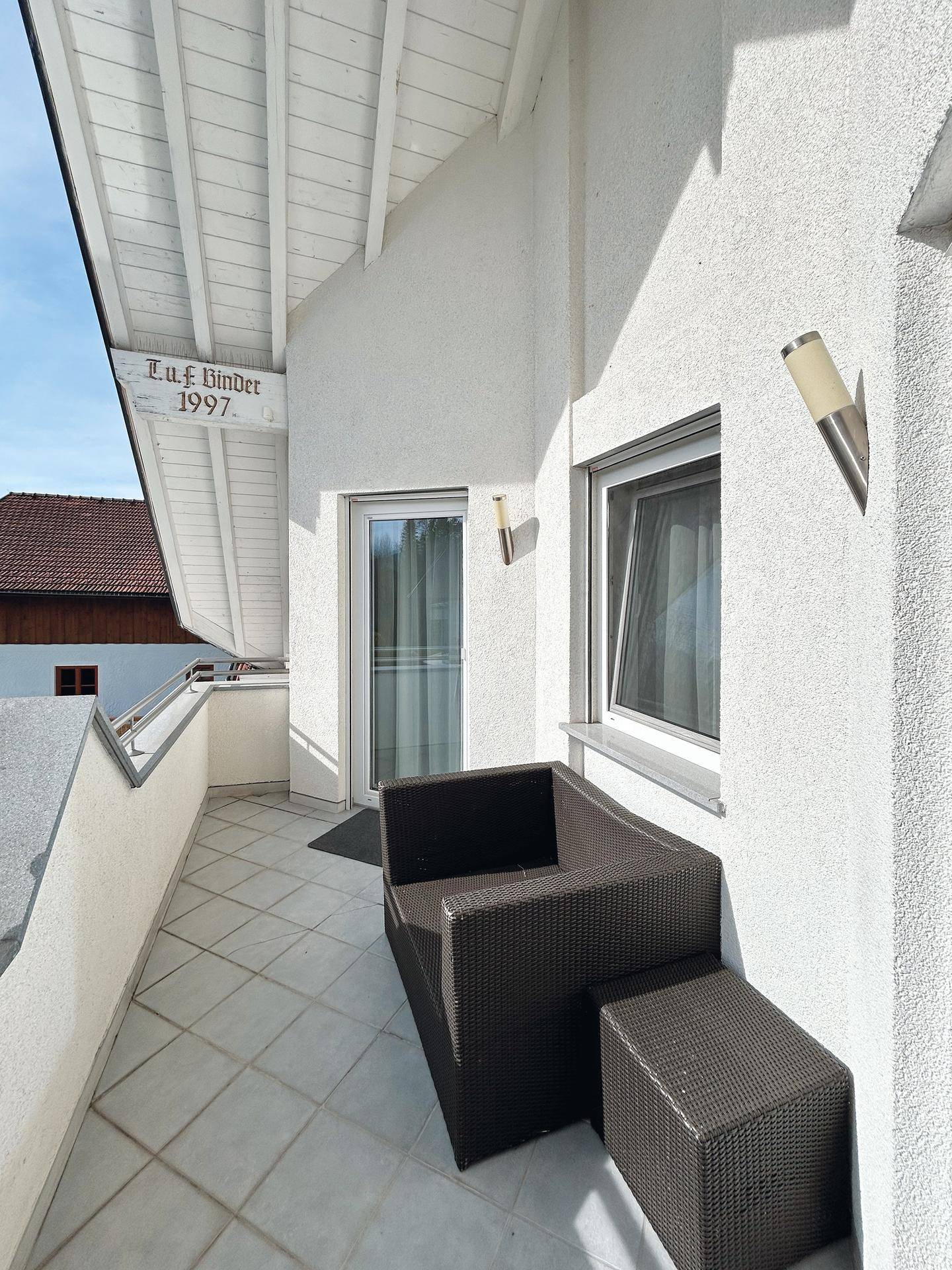 Kleiner Balkon mit Sitzgelegenheiten und Fliesenboden, ideal für entspannte Stunden im Freien.