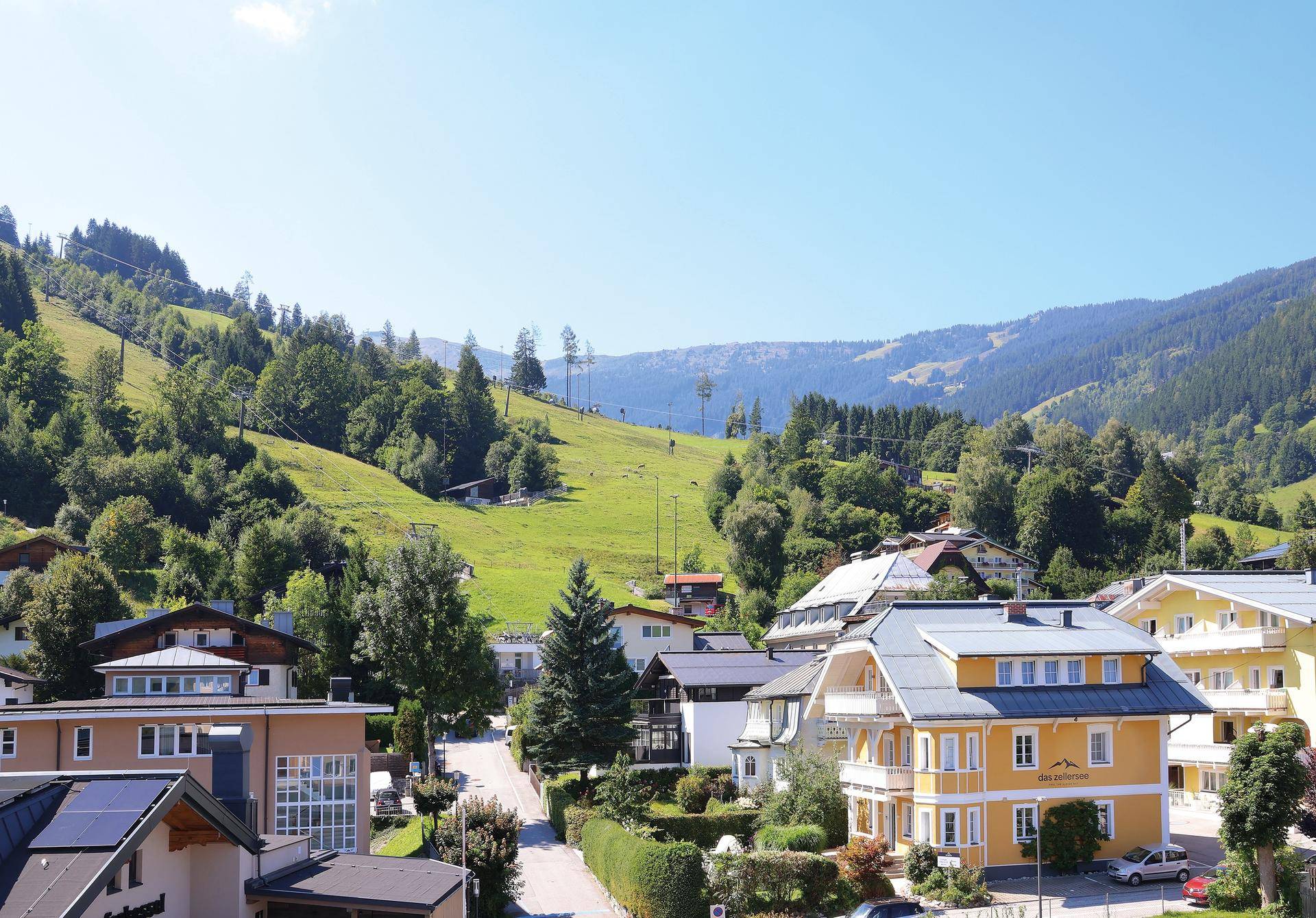 Malerisches Dorf in den Bergen mit traditionellen Häusern und grünen Hängen unter blauem Himmel.