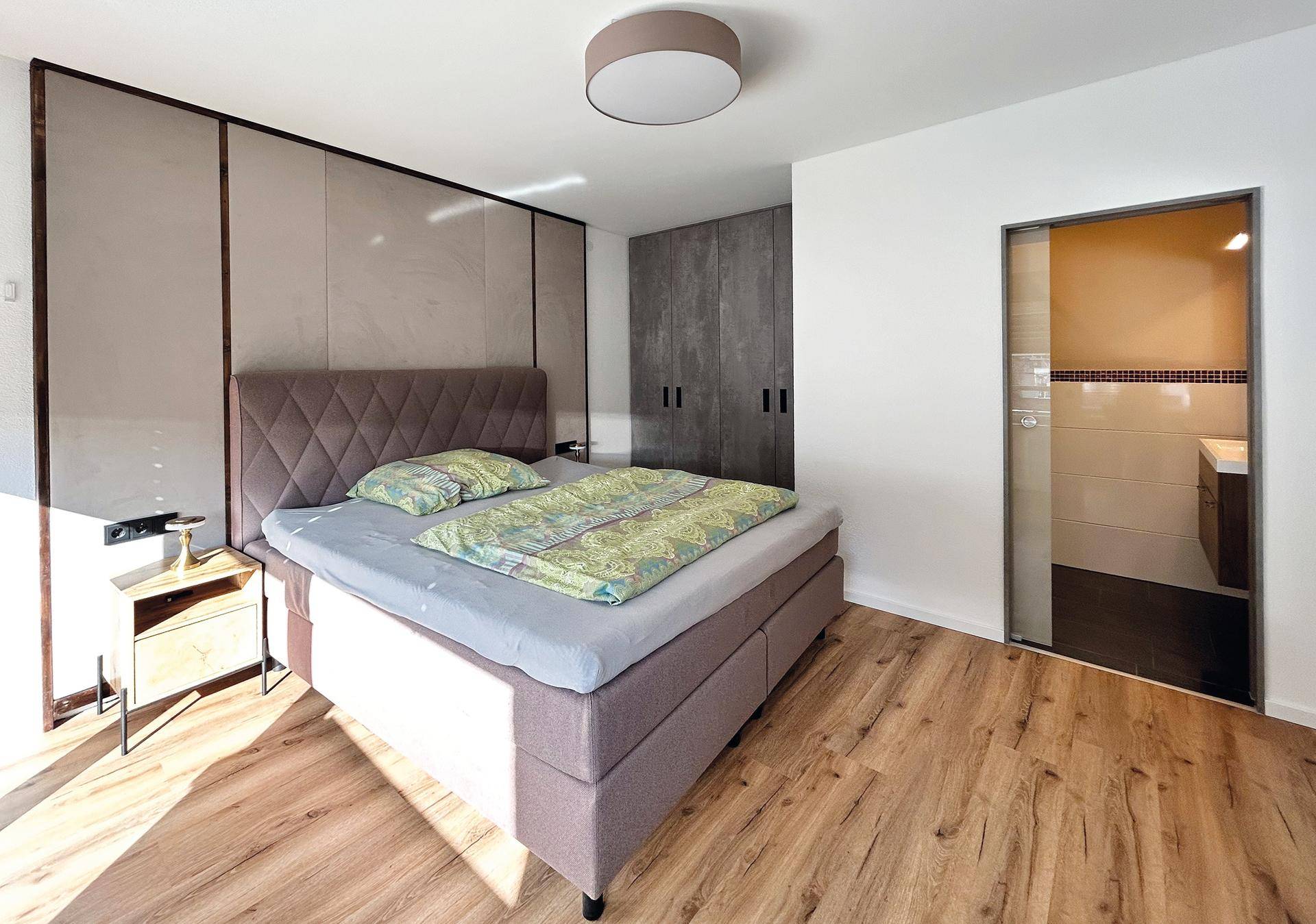Gemütliches Schlafzimmer mit großem Bett, Einbauschränken und Zugang zu einem Badezimmer.