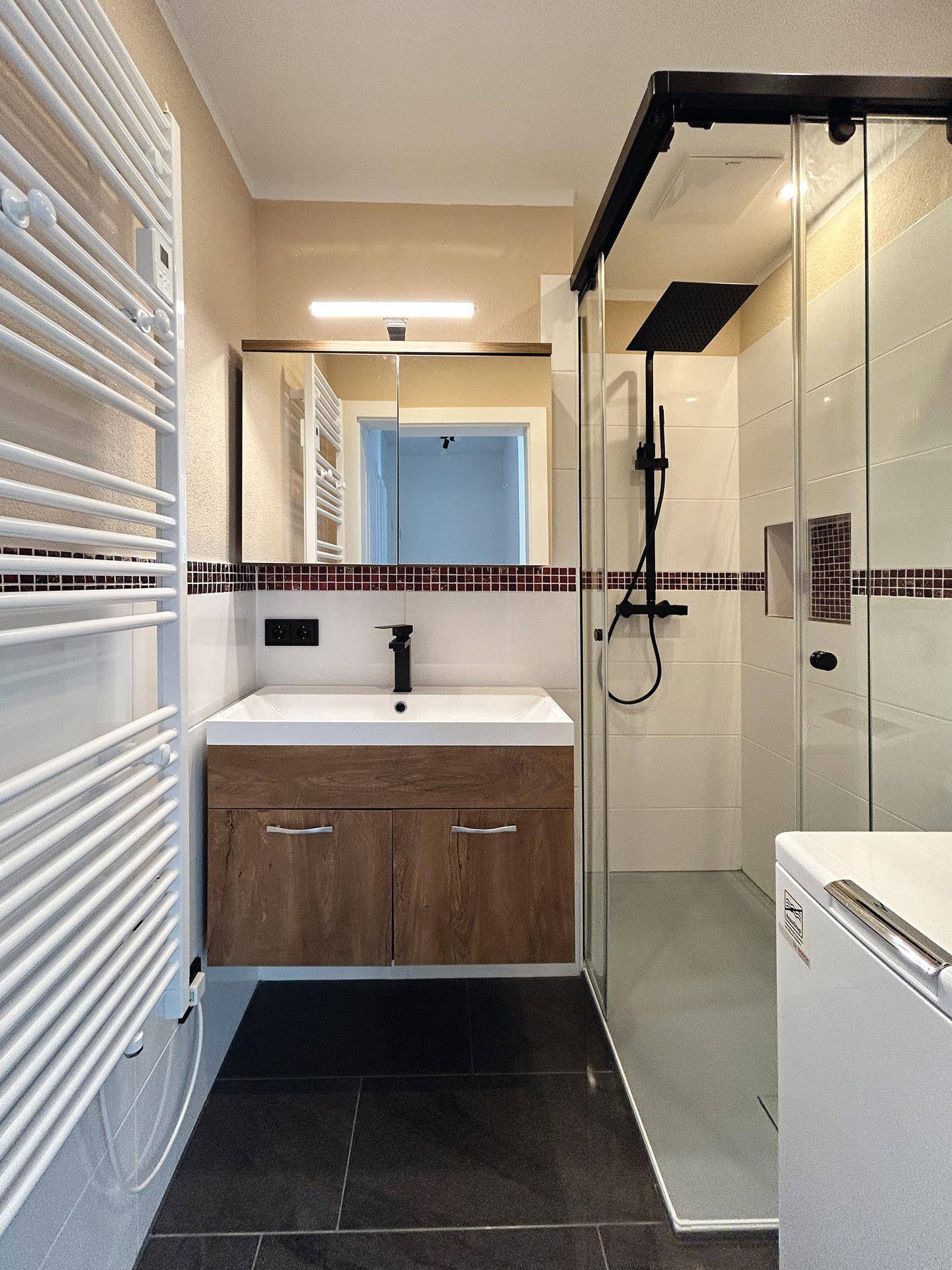 Modernes Badezimmer mit ebenerdiger Dusche, Einzelwaschbecken und beheiztem Handtuchhalter.