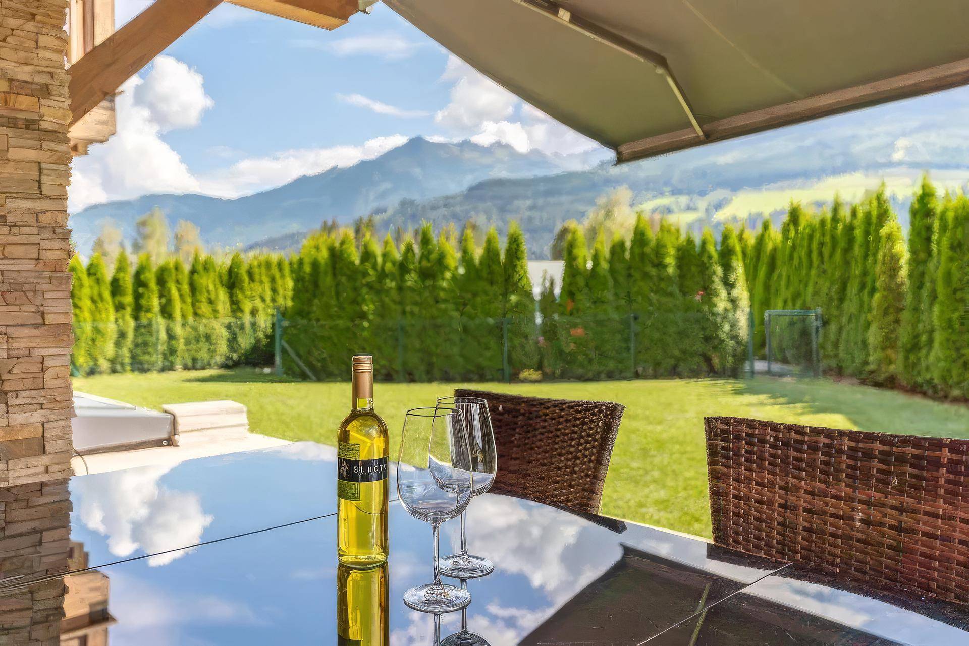 Sonniger Terrassenbereich mit Sitzgelegenheiten und einem weiten Blick auf die Berge.